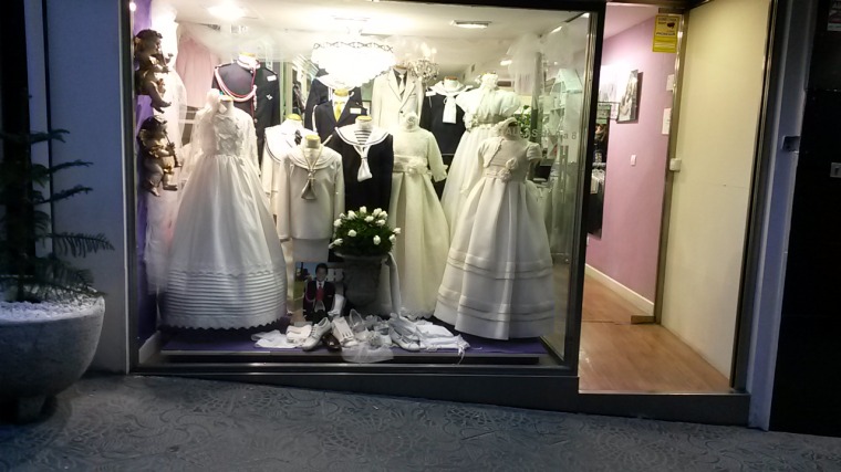 Schaufenster eines Kindermoden-Geschäftes mit Kommunionkleidern und -anzügen